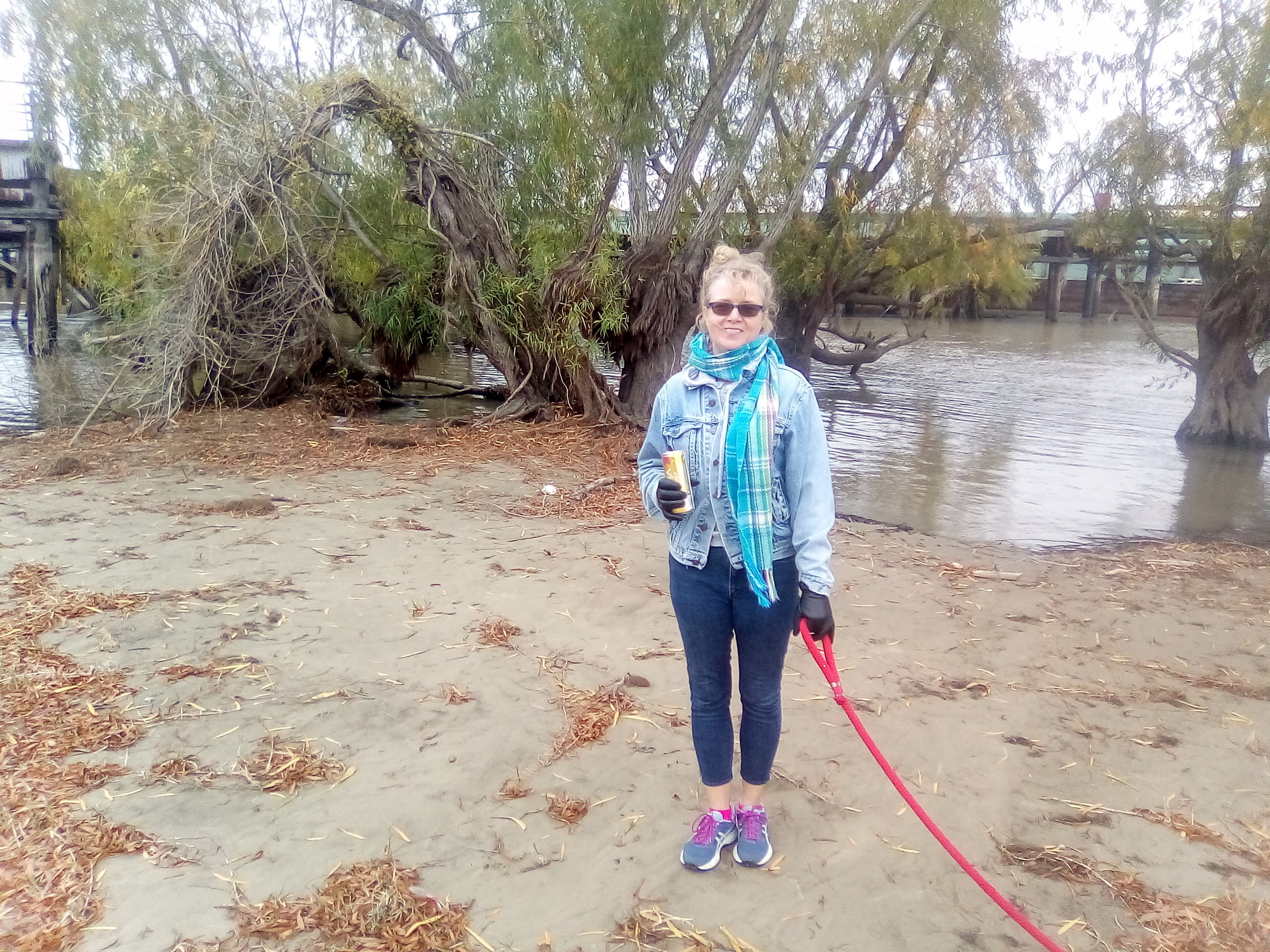 Gina Phillips on the river bank hlding a leash